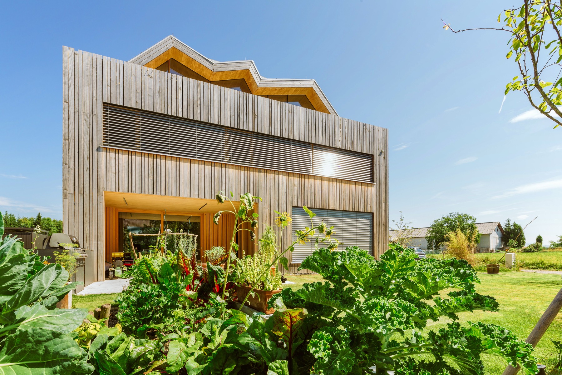 Timber home with automated exterior blinds shading the upper windows on a sunny day